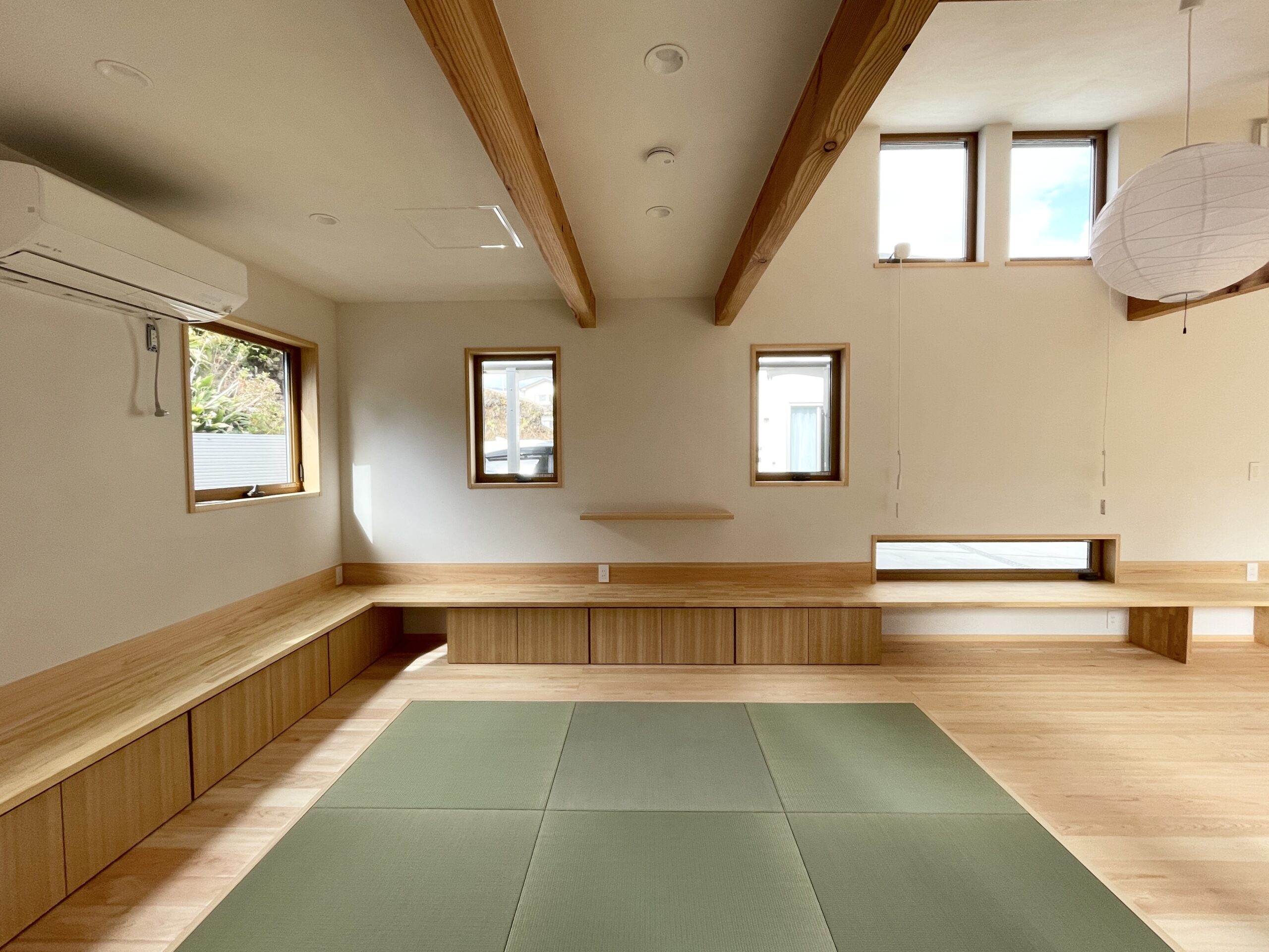 静岡県沼津市中沢田に建築したコの字型間取りプランの平家の自然素材の家。 夏や梅雨時は湿気や熱を排気、冬は太陽熱で温めた外気を床下に送り換気をしながら床暖房するソーラーシステムそよ風で家中足元から温めます。 全室壁天井は調湿消臭効果が高い珪藻土、床は檜フローリングなど自然素材仕上げ。 自然素材とソーラーシステムそよ風の相乗効果で湿気が少なく夏涼しく冬暖かい明るく風通しのいいパッシブデザインの環境共生住宅です。 画像はリビングの畳コーナー。 造作収納を造り付けで作成