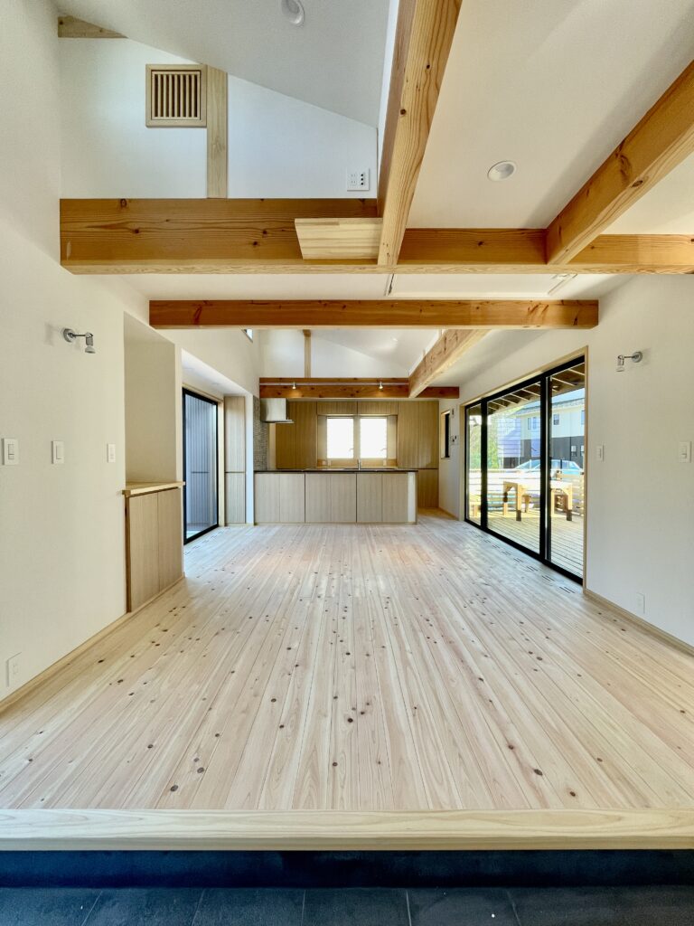 [山梨県八ヶ岳南麓北杜市長坂に建築したパッシブデザインの自然素材の家　建築設計施工事例]自然素材の家　別荘　注文住宅専門の建築設計事務所と建てるソーラーシステムそよ風で床暖房するサステナブルな環境共生住宅 コの字型間取りプラン 画像はウッドデッキの中庭と北側のバックヤードが隣接する吹抜けのLDK 玄関続きの土間には薪ストーブを設置 明るく風通しのいい夏涼しく冬暖かいリビングです