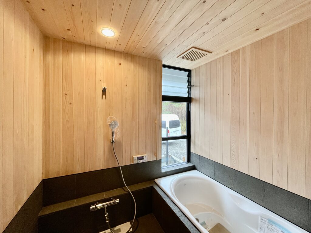 [山梨県八ヶ岳南麓北杜市長坂に建築したパッシブデザインの自然素材の家　建築設計施工事例]自然素材の家　別荘　注文住宅専門の建築設計事務所と建てるソーラーシステムそよ風で床暖房するサステナブルな環境共生住宅 コの字型間取りプラン 画像は玄関 お施主様支給の無垢の板をベンチに利用 木製格子の玄関ドアはオーダー品でオリジナルデザイン ウォークスルークローゼットと土間リビング、ホームオフィスに繋がります 床は３００角の御影石で夏はひんやり冬は床暖房で足元から暖かい玄関です