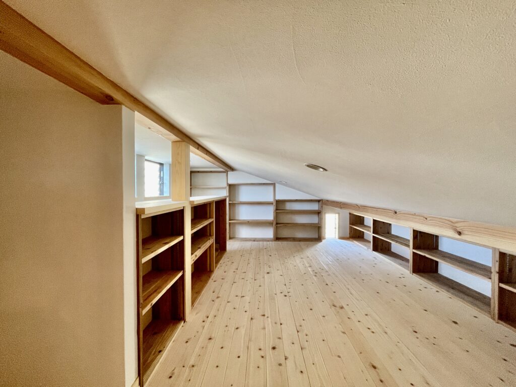 [山梨県八ヶ岳南麓北杜市長坂に建築したパッシブデザインの自然素材の家　建築設計施工事例]自然素材の家　別荘　注文住宅専門の建築設計事務所と建てるソーラーシステムそよ風で床暖房するサステナブルな環境共生住宅 コの字型間取りプラン 画像は本棚を造り付けで作成したロフト