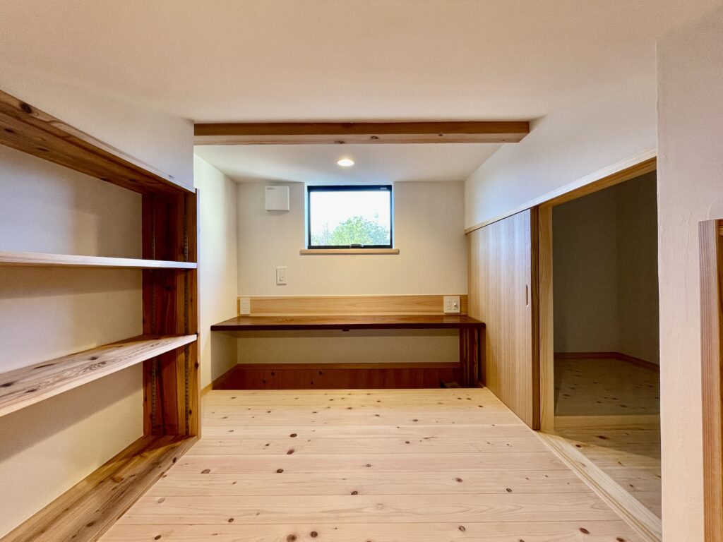 [山梨県八ヶ岳南麓北杜市長坂に建築したパッシブデザインの自然素材の家　建築設計施工事例]自然素材の家　別荘　注文住宅専門の建築設計事務所と建てるソーラーシステムそよ風で床暖房するサステナブルな環境共生住宅 コの字型間取りプラン 画像は掘り炬燵式のカウンター机と本棚を造り付けで作成したロフトの書斎スペース