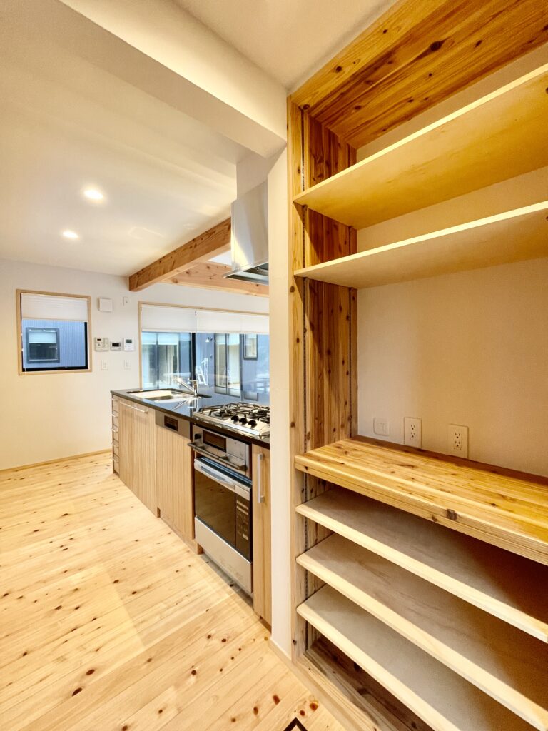[山梨県八ヶ岳南麓北杜市長坂に建築したパッシブデザインの自然素材の家　建築設計施工事例]自然素材の家　別荘　注文住宅専門の建築設計事務所と建てるソーラーシステムそよ風で床暖房するサステナブルな環境共生住宅 コの字型間取りプラン 画像は御影石天板の造作キッチンと食器棚 バックヤードに出入りできる勝手口があるパントリーが隣接 パントリーは電子レンジなど家電も置けるように専用のコンセントを設置