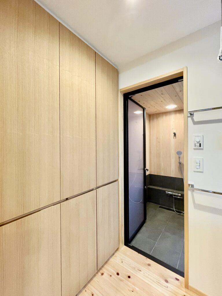 [山梨県八ヶ岳南麓北杜市長坂に建築したパッシブデザインの自然素材の家　建築設計施工事例] 　自然素材の家　別荘　注文住宅専門の建築設計事務所と建てるソーラーシステムそよ風で床暖房するサステナブルな環境共生住宅 画像は下着やバスタオル　洗剤などスッキリしまえる収納棚を造り付けで作成した脱衣室