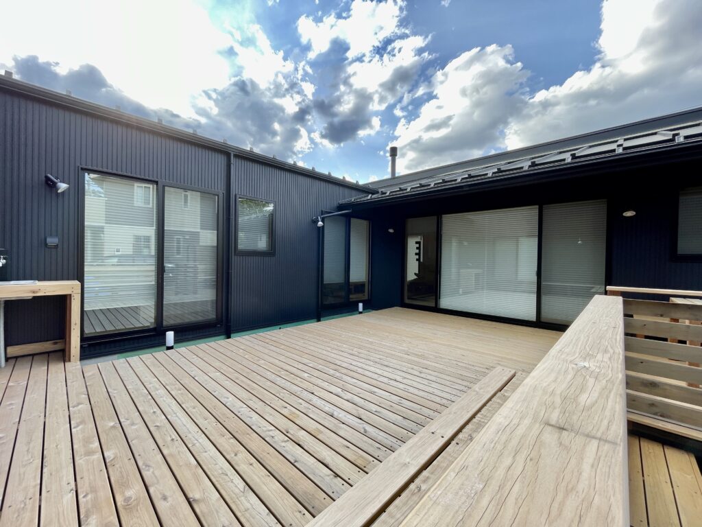 [山梨県八ヶ岳南麓北杜市長坂に建築したパッシブデザインの自然素材の家　建築設計施工事例] 　自然素材の家　別荘　注文住宅専門の建築設計事務所と建てるソーラーシステムそよ風で床暖房するサステナブルな環境共生住宅 平屋のコの字型間取りプラン 画像は木の塀で目隠ししたウッドデッキの中庭