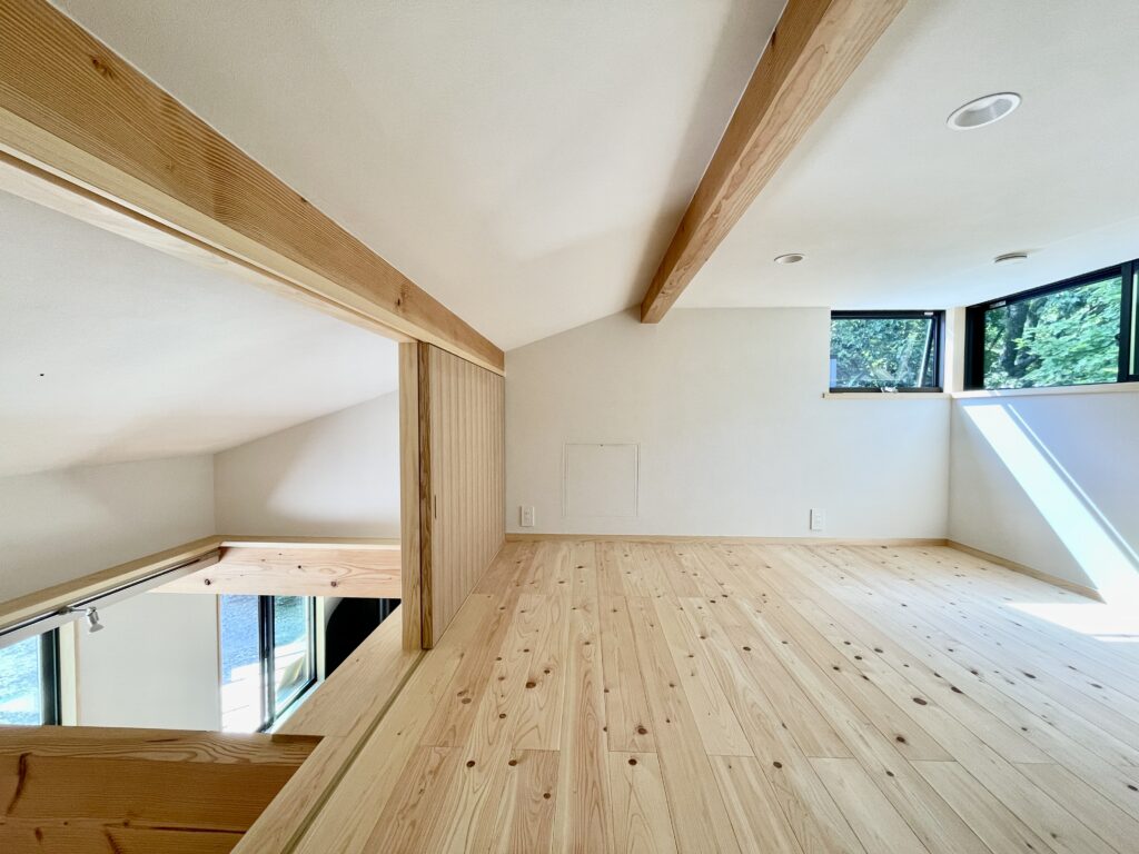 静岡県東部裾野市十里木高原に建築したソーラーシステムそよ風で床暖房するパッシブデザインのサステナブルな自然素材の家 ビルとインナーガレージ 広いウッドデッキ 富士山一望のロフト リビング土間に薪ストーブなど家の中もアウトドアも楽しめる環共生住宅 画像はコーナーサッシから富士山一望のリビングロフト 引戸でリビングと間仕切りできます 壁天井は消臭調湿効果が高い珪藻土、床は無垢の桧フローリング
