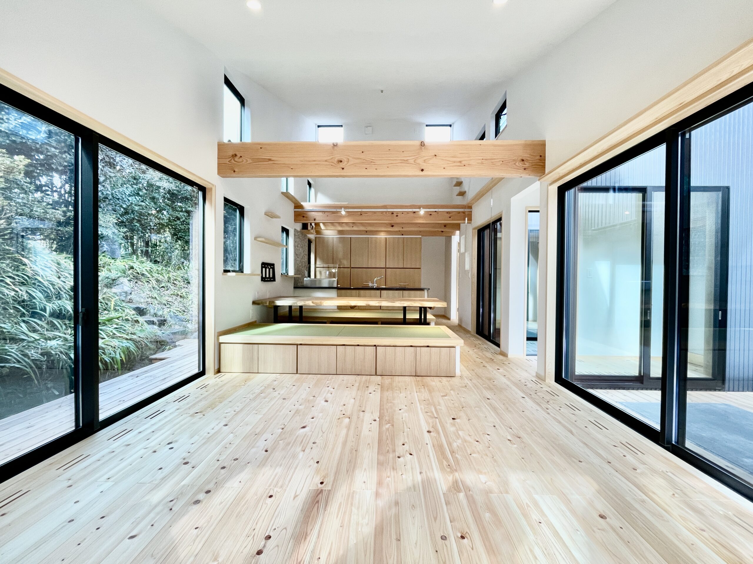 静岡県東部小山町菅原に建築したパッシブデザインの平家の自然素材の家 坪庭と中庭で母屋とゾーン分けした間取り設計の離れ増築 シンプル和風モダンデザインのインテリア 消臭調湿効果が高い珪藻土、無垢の桧フローリングなど天然素材仕上げ 御影石天板の造作キッチンと一体化するように畳ベンチと無垢テーブルを造り付けで作成 温風式の床暖房とウッドデッキに出入りできる床暖房の土間に設置した薪ストーブで家中足元から暖かくします 東西南北と高窓からの通風と採光で明るく風通しのいいリビングです 土間から吹抜けの高窓まで猫階段とキャットウォークで行き来でき猫も楽しく快適なサステナブル住宅です