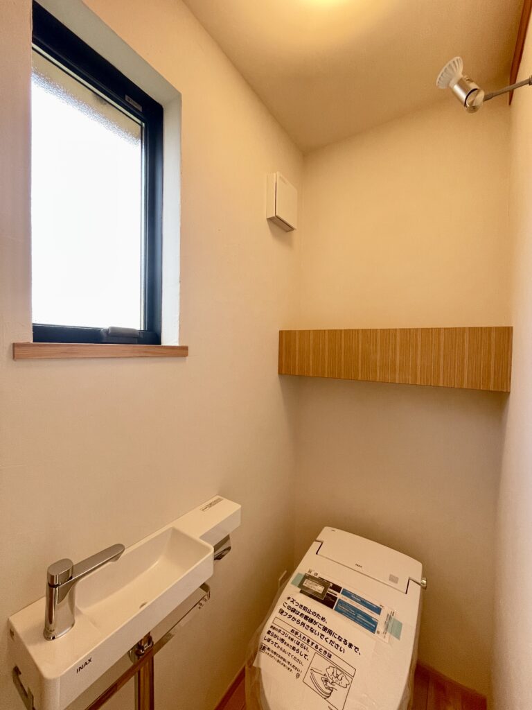 神奈川県鎌倉市西鎌倉に建築したL字型間取り設計の自然素材の家。夏や梅雨時は湿気や熱を排気し、冬は太陽熱で温めた外気を床下に送り換気をしながら床暖房するソーラーシステムそよ風で家中足元から暖かくします。壁天井は消臭調湿効果が高い珪藻土、床は桧フローリングなど天然素材仕上げ。自然素材とソーラーシステムそよ風の相乗効果で湿気が少なく夏涼しく冬暖かいパッシブデザインの環境共生住宅です。 全室収納は造り付けで作成したのでスッキリものが片付き使い勝手と住み心地がいいサステナブルハウス。 画像は２階のトイレ