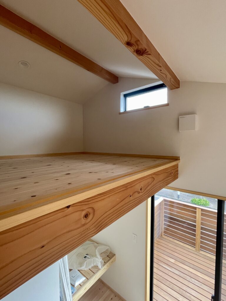 神奈川県鎌倉市西鎌倉に建築したL字型間取り設計の自然素材の家。夏や梅雨時は湿気や熱を排気し、冬は太陽熱で温めた外気を床下に送り換気をしながら床暖房するソーラーシステムそよ風で家中足元から暖かくします。壁天井は消臭調湿効果が高い珪藻土、床は桧フローリングなど天然素材仕上げ。自然素材とソーラーシステムそよ風の相乗効果で湿気が少なく夏涼しく冬暖かいパッシブデザインの環境共生住宅です。 全室収納は造り付けで作成したのでスッキリものが片付き使い勝手と住み心地がいいサステナブルハウス。 画像は２階の湘南海岸が一望できるロフトがあるホームオフィス。カウンター机や本棚を造り付けで作成。テレワーク・リモートワークなど在宅勤務でもストレスなく仕事がこなせます。外はウッドデッキのバルコニーで木のスリット塀で道路側から見えないようにしプライバシーを確保。