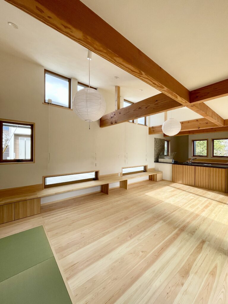 静岡県東部沼津市に建築したコの字型間取り設計の平家の自然素材の家。夏や梅雨時は湿気や熱を排気し、冬は太陽熱で温めた外気を床下に送り換気をしながら床暖房するソーラーシステムそよ風で家中足元から暖かくします。壁天井は消臭調湿効果が高い珪藻土、床は桧フローリングなど天然素材仕上げ。自然素材とソーラーシステムそよ風の相乗効果で湿気が少なく夏涼しく冬暖かいパッシブデザインの環境共生住宅です。 全室収納は造り付けで作成したのでスッキリものが片付き使い勝手と住み心地がいいサステナブルハウス。 画像は東西南北と高窓からの通風と採光で明るく風通しのいい中庭が隣接した吹抜けリビング。