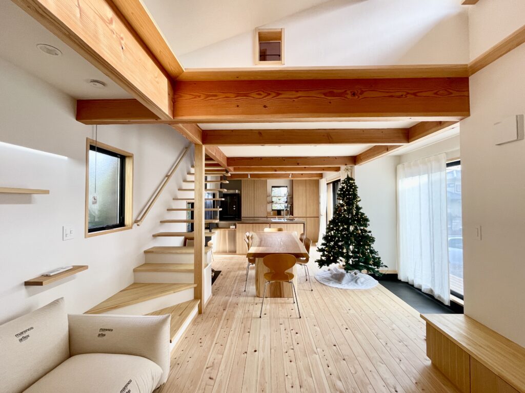 神奈川県鎌倉市西鎌倉に建築したL字型間取り設計の自然素材の家。夏や梅雨時は湿気や熱を排気し、冬は太陽熱で温めた外気を床下に送り換気をしながら床暖房するソーラーシステムそよ風で家中足元から暖かくします。壁天井は消臭調湿効果が高い珪藻土、床は桧フローリングなど天然素材仕上げ。自然素材とソーラーシステムそよ風の相乗効果で湿気が少なく夏涼しく冬暖かいパッシブデザインの環境共生住宅です。 全室収納は造り付けで作成したのでスッキリものが片付き使い勝手と住み心地がいいサステナブルハウス。 画像はウッドデッキに隣接した土間がある吹抜けのリビング。