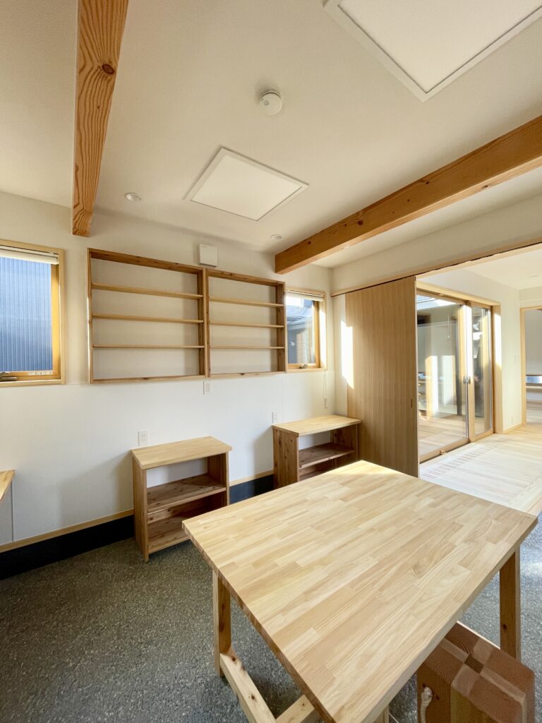 静岡県東部沼津市に建築したコの字型間取り設計の平家の自然素材の家。夏や梅雨時は湿気や熱を排気し、冬は太陽熱で温めた外気を床下に送り換気をしながら床暖房するソーラーシステムそよ風で家中足元から暖かくします。壁天井は消臭調湿効果が高い珪藻土、床は桧フローリングなど天然素材仕上げ。自然素材とソーラーシステムそよ風の相乗効果で湿気が少なく夏涼しく冬暖かいパッシブデザインの環境共生住宅です。 全室収納は造り付けで作成したのでスッキリものが片付き使い勝手と住み心地がいいサステナブルハウス。 画像は玄関土間続きの陶芸アトリエ。ろくろが２台置けるスペースがあり収納棚や展示だなは造り付けで作成。