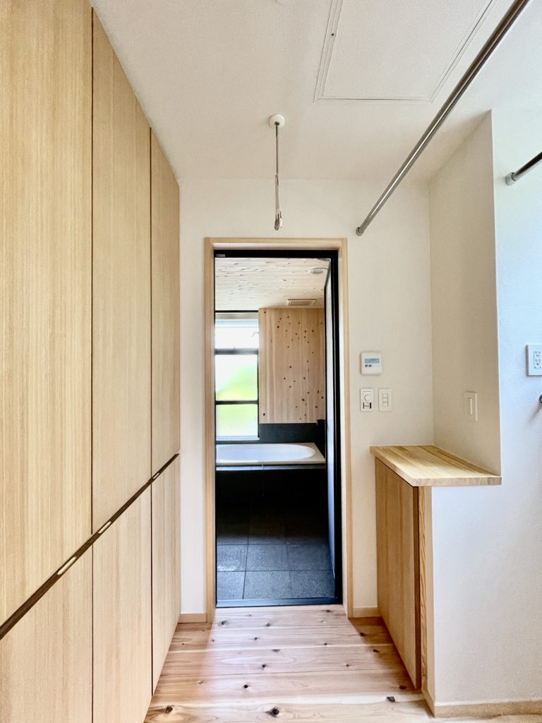 山梨県山中湖讃美ヶ丘別荘地に建築したソーラーシステムそよ風で床暖房する平家の自然素材の家。
山中湖一望!リビングロフト空間やワンコが遊べる屋根付きの広いウッドデッキで内と外が楽しめる別荘・セカンドハウス。
夏や梅雨時は湿気や熱を排気し、冬は太陽熱で温めた外気を床下に送り換気をしながら床暖房するソーラーシステムそよ風とウッドデッキから出入りできる土間に設置した薪ストーブで家中足元から暖かくします。
太陽の熱 光 風の流れなど自然エネルギー 気候風土を考慮したパッシブデザイン設計で明るく風通しのいい爽やかなサステナブル住宅。
全室壁天井は消臭調湿効果が高い珪藻土、床は無垢の杉フローリングなど天然素材仕上げ。
留守中も自然素材とソーラーシステムそよ風の相乗効果で湿気が少なく夏涼しく冬暖かい環境共生住宅です。
造り付け収納でスッキリ物が片付き使い勝手と住み心地のいい移住定住型の別荘・セカンドハウス。
画像は下着やバスタオルがしまえる収納棚と洗剤やバケツが置ける収納棚がある脱衣室
上部は洗濯物室内干し用のパイプ