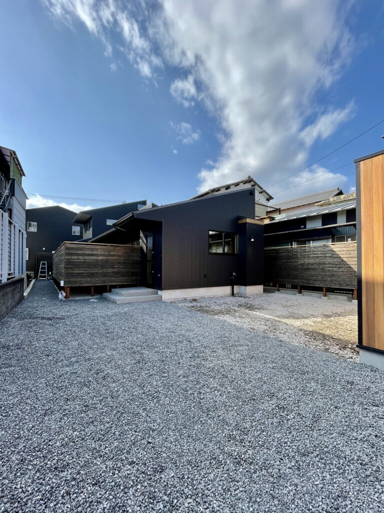静岡県東部裾野市佐野に建築したパッシブデザインの自然素材の家建築設計施工事例。 主な特徴は ・レッドシダー羽目板のゲート ・木の塀で目隠ししたウッドデッキの中庭 ・鉄骨のリビング階段 ・ウッドデッキの洗濯物干しと布団干しスペース ・シューズクローク ・ウォークインクローゼット ・テレワーク・リモートワークスペース ・キッチンシンクを組み込んだ造作洗面化粧台 ・御影石と檜の羽目板仕上げの浴室 ・富士山一望のロフト ・富士山一望のルーフバルコニー 全室消臭調湿効果が高い珪藻土 床は無垢の桧フローリングなど天然素材仕上げ。 収納がたくさんあって使い勝手が良く住み心地がいいサステナブルな自然素材の家です。 画像は縦ストライプのガルバリウムのシンプルモダンデザインの外観