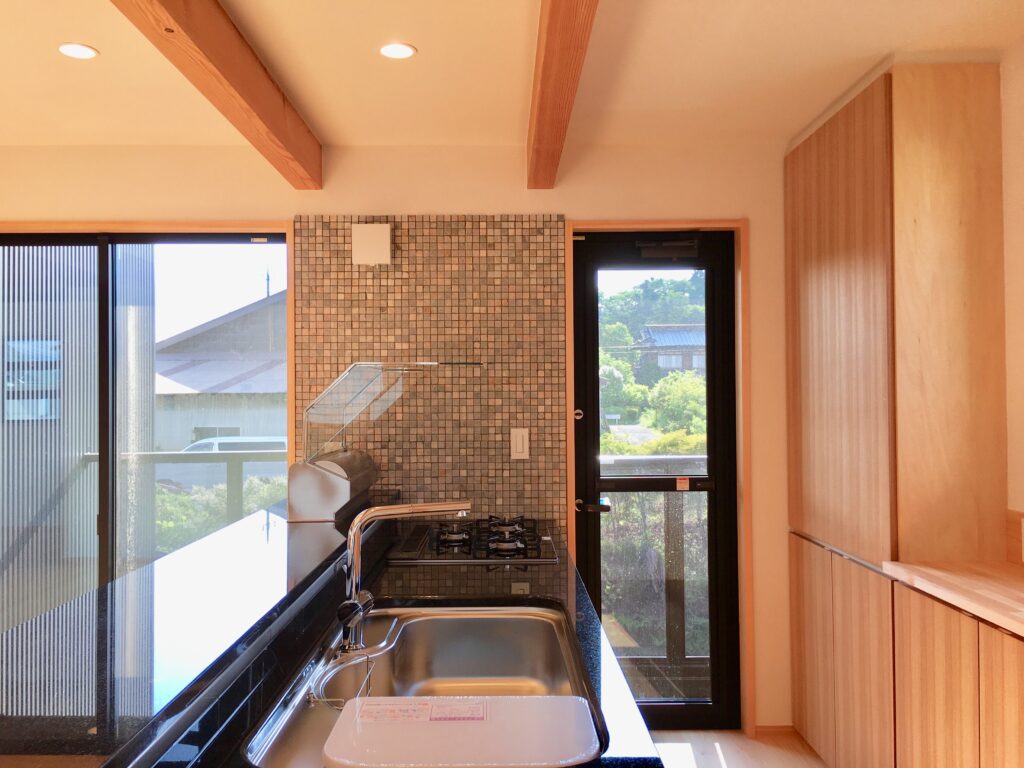小山町用沢に建築したソーラーシステムそよ風で床暖房する2階リビングの自然素材の家 画像は御影石天板の造作キッチンと造り付けで作成した食器棚 グレーチングのルーフバルコニーが隣接しアウトドアも楽しめます。