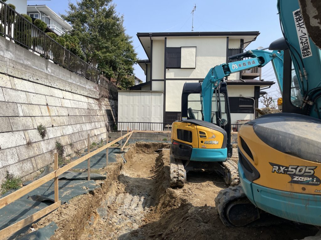 神奈川県鎌倉市西鎌倉のソーラーシステムそよ風で床暖房するパッシブデザインの自然素材の家。 自然素材の家　別荘注文住宅専門の一級建築士事務所　探彩工房建築設計事務所と建てるサステナブルな環境共生住宅の建築設計施工事例。 L字型間取りプランで湘南海岸一望！ 画像は重機で基礎を作るため地盤を掘削している様子