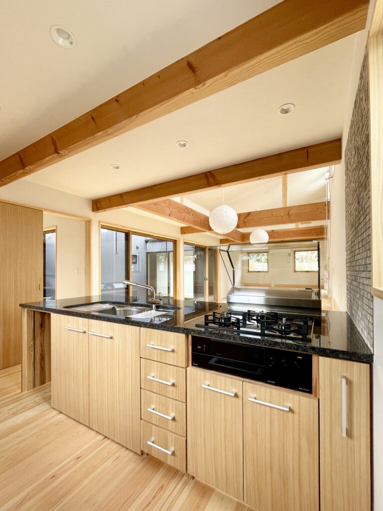 静岡県東部沼津市に建築したコの字型間取りの自然素材の家 。梅雨時や夏は熱気や湿気を排気し冬は太陽熱で温めた外気を床下に送り換気をしながら床暖房するソーラーシステムそよ風で家中足元から暖かい環境共生住宅です。 全室壁天井は消臭調湿効果が高い珪藻土床は桧のフローリングなど天然素材仕上げ 。自然素材とソーラーシステムそよ風の相乗効果で湿気が少なく夏涼しく冬暖かい明るく風通しのいいパッシブデザインの注文住宅 。全室収納を造り付けで作成しスッキリものが片付き使い勝手と居心地がいいサステナブルハウス 。画像は御影石天板の造作キッチン。吸い込みがよく掃除などメンテナンスが楽なグリーンハイキを採用。幅2.７３m奥行き1.０mの対面式ペニンシュラ型キッチンです。