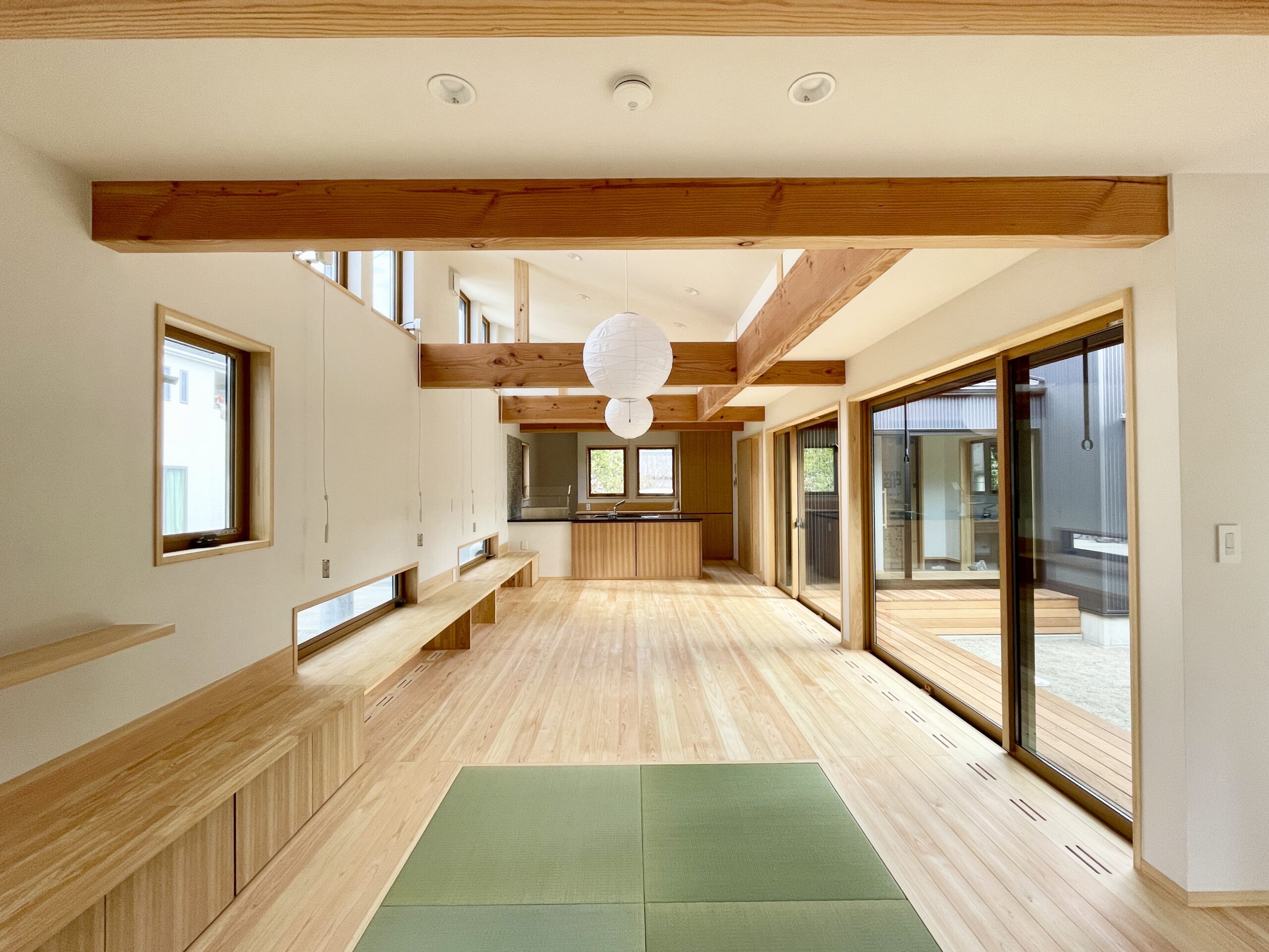 静岡県東部沼津市に建築したコの字型間取りの自然素材の家 。梅雨時や夏は熱気や湿気を排気し冬は太陽熱で温めた外気を床下に送り換気をしながら床暖房するソーラーシステムそよ風で家中足元から暖かい環境共生住宅です。 全室壁天井は消臭調湿効果が高い珪藻土床は桧のフローリングなど天然素材仕上げ 。自然素材とソーラーシステムそよ風の相乗効果で湿気が少なく夏涼しく冬暖かい明るく風通しのいいパッシブデザインの注文住宅 。全室収納を造り付けで作成しスッキリものが片付き使い勝手と居心地がいいサステナブルハウス 。画像は畳コーナがある吹抜けリビング。東西南北と高窓からの通風と採光で明るく風通しのいい空間です。